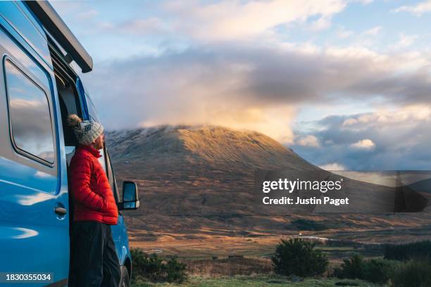 side view of a mature man looking at the sunset view of the scottish highlands from his campervan - blue coat stock pictures, royalty-free photos & images