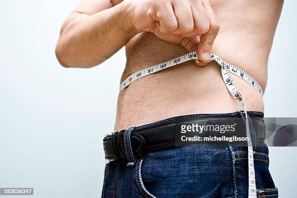 shirtless man measuring his waist with a measuring tape - mass unit of measurement stock pictures, royalty-free photos & images