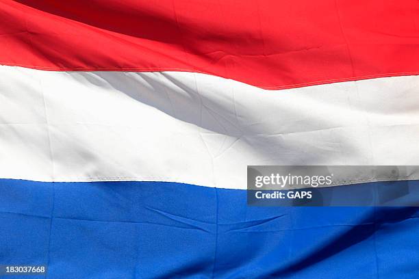 a red, white and blue netherlands flag flying proudly - nederlandse vlag stockfoto's en -beelden