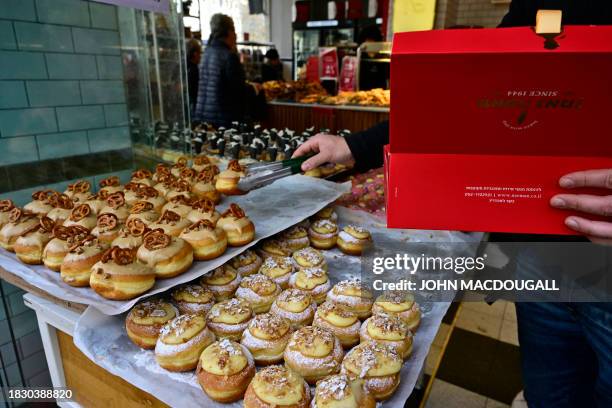 Man buys sufganiyot, a round jelly doughnut eaten in Israel and around the world on the Jewish festival of Hanukkah, at a bakery in Jerusalem on...