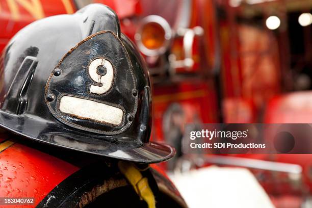 feuerwehrmann helm ruhen auf feuerwehrwagen - feuerwehrhelm stock-fotos und bilder