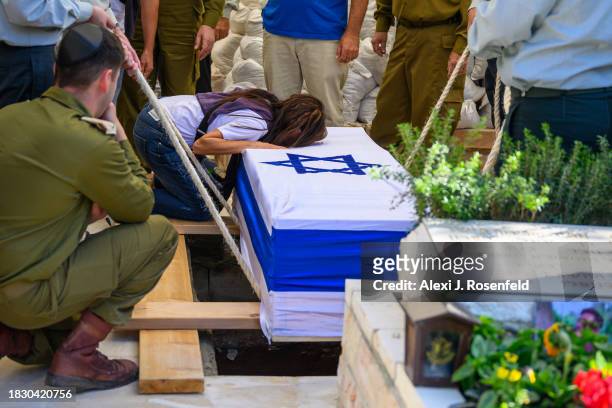 The mother of Col. Asaf Hamami, commander of Gaza Division's Southern Brigade, places her head on the casket during his funeral at the Kiryat Shaul...