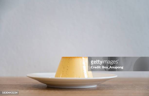 a sweet pudding served in a plate on table against the white wall. - プリン ストックフォトと画像