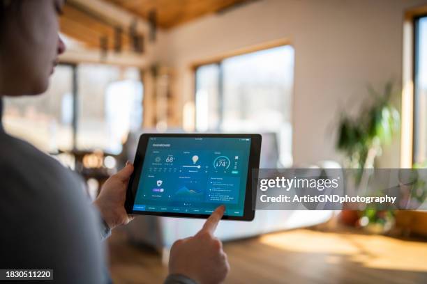 woman using tablet with smart home control functions. - domotica stockfoto's en -beelden