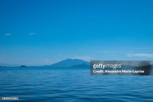 blue coastline seen from afar with a volcanic mountain, lush vegetation forest and a calm ocean - salvadorianische kultur stock-fotos und bilder