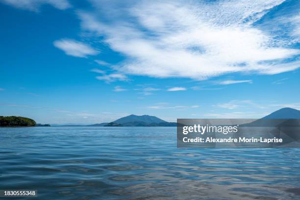 tiny islands seen from afar with volcanic mountains, lush vegetation forest, beach in front of a calm ocean in fonseca gulf - salvadorianische kultur stock-fotos und bilder