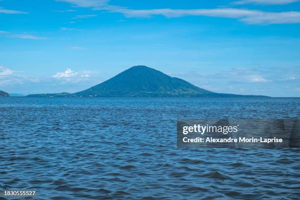 volcanic mountain with lush vegetation forest in front of a calm blue ocean - salvadorianische kultur stock-fotos und bilder