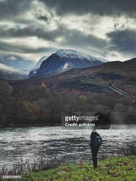 rear view of a woman looking at mountain ben nevis  from river lochy, scotland - summit stock pictures, royalty-free photos & images