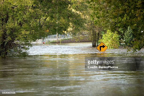 flooded river over a city street - flood stockfoto's en -beelden