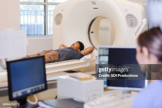 man lies on bed as radiographer prepares to start scan - outpatient care bildbanksfoton och bilder