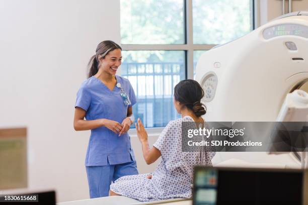 cat-technikerin lächelt, als unbekannte patientin spricht - computertomogramm stock-fotos und bilder