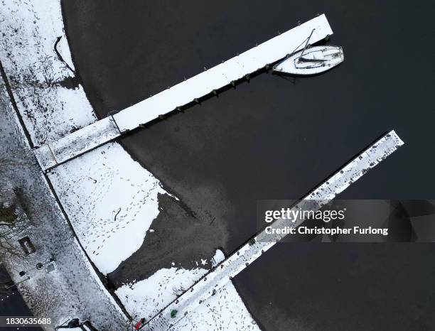 Recent snow, freezing temperatures and a heavy sky create a monochromatic scene over Lake Windermere and its sailing jettys atb Ambleside, Cumbria on...