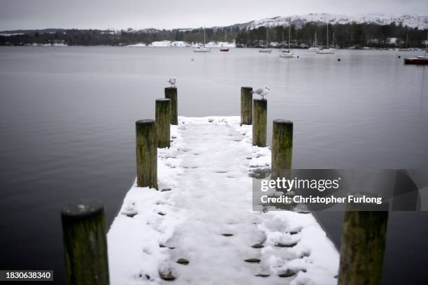 Recent snow, freezing temperatures and a heavy sky create a monochromatic scene over Lake Windermere and its sailing jetties at Ambleside, Cumbria on...