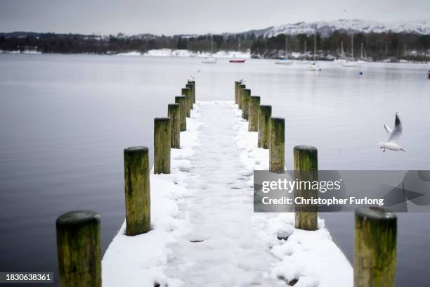 Recent snow, freezing temperatures and a heavy sky create a monochromatic scene over Lake Windermere and its sailing jetties at Ambleside, Cumbria on...