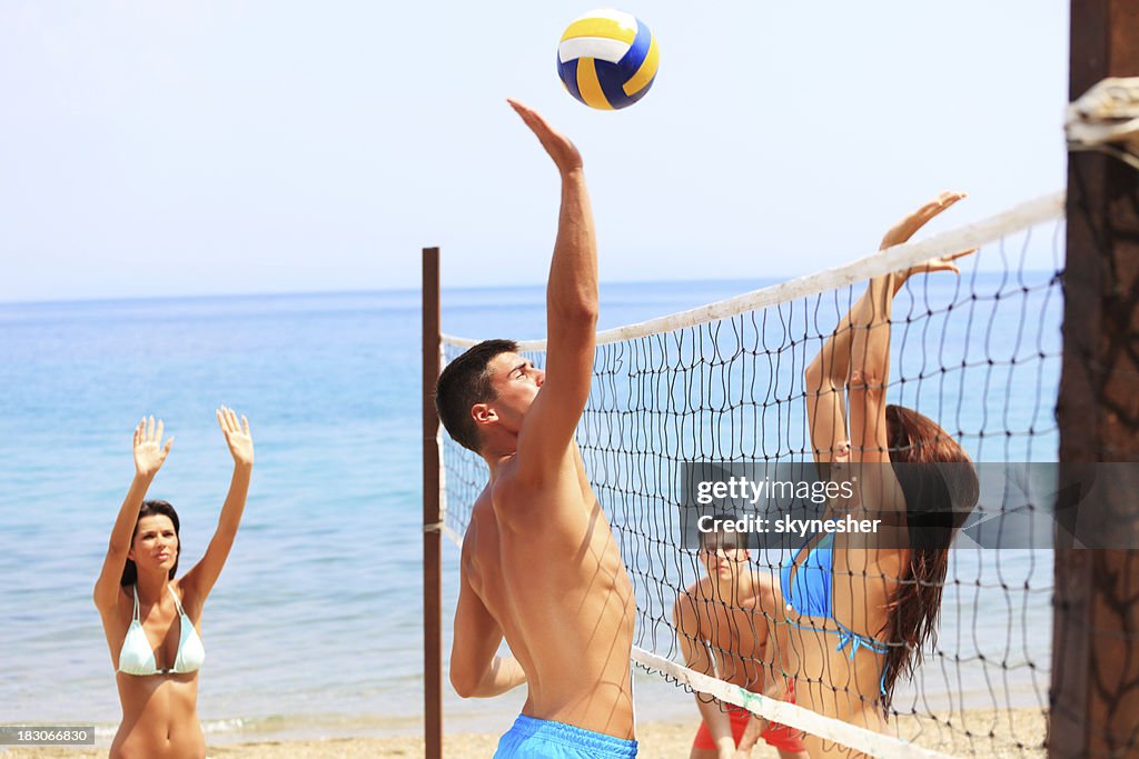 Team plays beach volleyball.