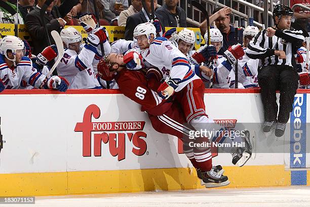 Mikkel Boedker of the Phoenix Coyotes is checked into the boards by Dan Girardi of the New York Rangers during the third period of the Coyotes' home...