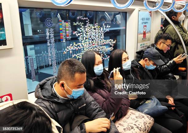 Passengers wait under a bilingual sign at Jianguomen subway station in Beijing, China, December 7, 2023. Signs in both Chinese and English have been...