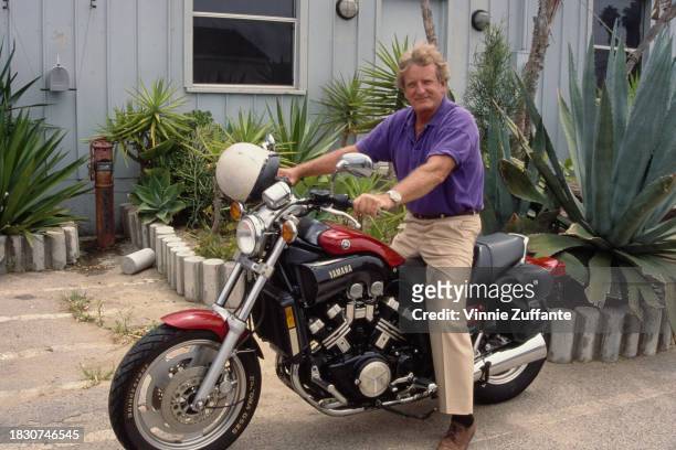 British-born American actor Nicolas Coster, wearing a purple polo shirt and beige trousers, sits astride a Yamaha VMAX motorcycle, in Burbank,...