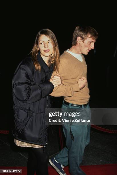 American film director and actress Sofia Coppola, wearing a black coat, walks arm-in-arm with American film director Spike Jonze, who wears a tan...