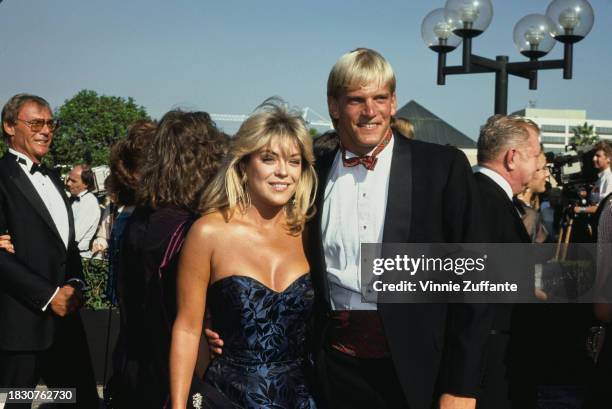 American actress Lydia Cornell, wearing a dark blue off-shoulder evening gown, with American swimmer Steve Lundquist, who wears a tuxedo and tartan...