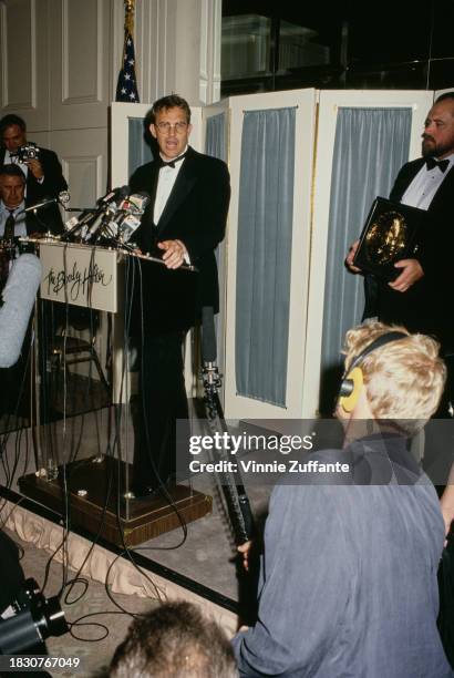 American actor and film director Kevin Costner, wearing a tuxedo and bow tie, speaking from a lectern as he addresses the press following the 43rd...