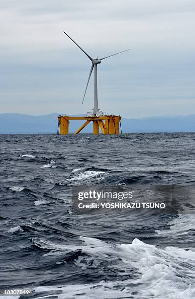 An offshore wind turbine 100m in height and bladespan of 40m, stands positioned in the sea off the coast of the town of Naraha in Fukushima...