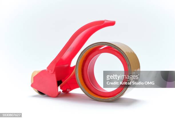 a red plastic adhesive tape cutter on white background - tape dispenser stock-fotos und bilder