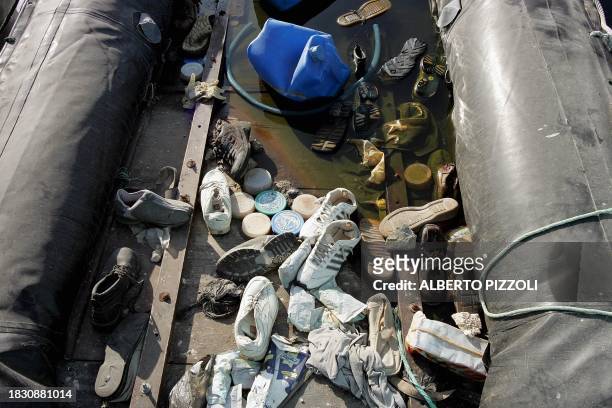 This picture taken 28 July 2004 shows abandoned shoes in a zodiac anchored at the immigrants boat-cemetery, in the harbour of Lampedusa. Italian...