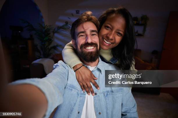 cheerful multiethnic couple taking a selfie together at home. - moonlight lovers stock pictures, royalty-free photos & images