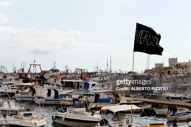 Black flag reading "Shame" in Italian flies in the Lampedusa harbour on October 4, 2013 a day after a boat with migrants sank killing more than...