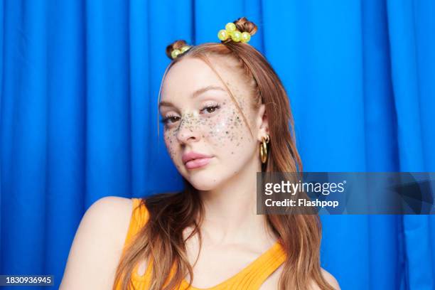 portrait of genz woman standing in front of a blue curtain background. - hoop earring stock pictures, royalty-free photos & images