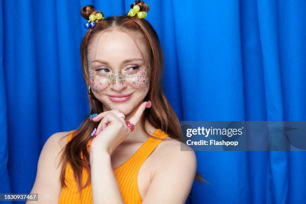 portrait of genz woman standing in front of a blue curtain background. - woman smiling white background stock pictures, royalty-free photos & images