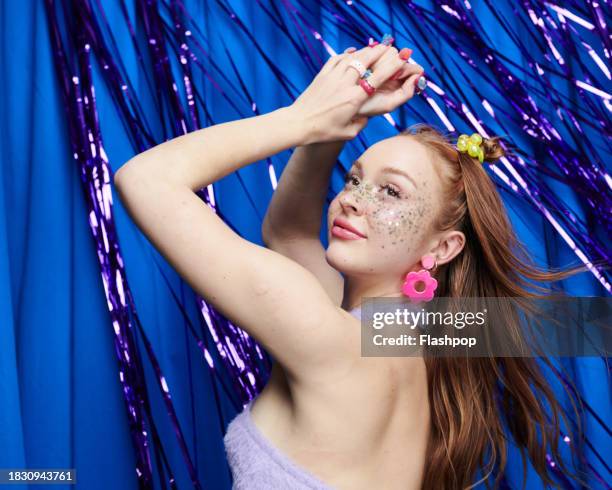 portrait of genz woman standing in front of a blue and purple metallic curtain background. - face arms stock pictures, royalty-free photos & images