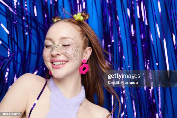 portrait of genz woman standing in front of a blue and purple metallic curtain background. - woman smiling white background stock pictures, royalty-free photos & images