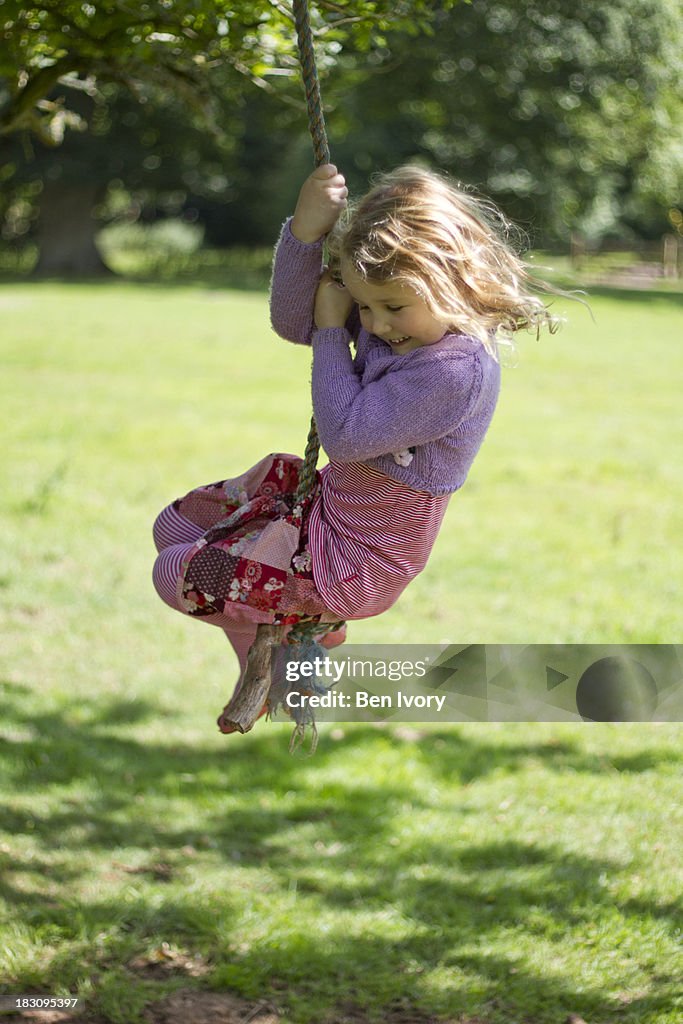 Young girl swinging on rope swing