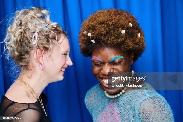 portrait of two fashionable people standing in front of a blue curtain. - lgbtq  female fotografías e imágenes de stock