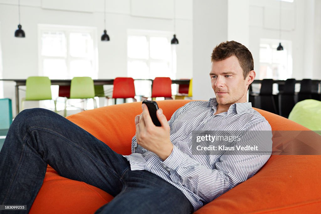 Portrait of man lying on beanbag with smartphone