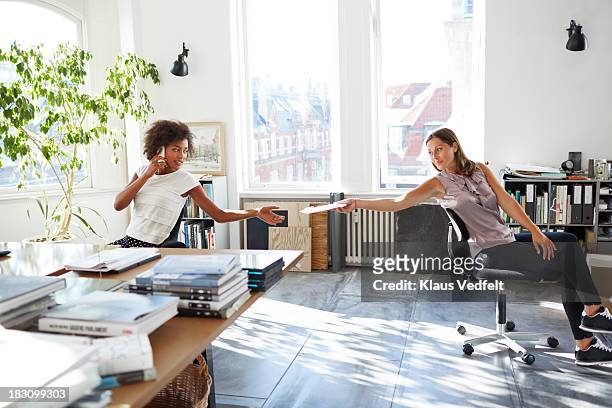coworkers passing papers between their desks - sfogliare libro foto e immagini stock