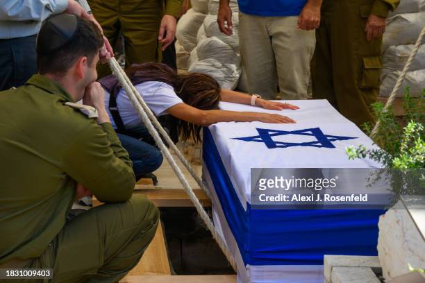 The mother of Col. Asaf Hamami, commander of Gaza Division's Southern Brigade, grasps the casket during his funeral at the Kiryat Shaul cemetery on...
