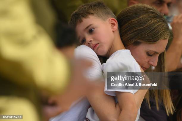 The wife of Col. Asaf Hamami, commander of Gaza Division's Southern Brigade, holds their son, Alon, during his funeral at the Kiryat Shaul cemetery...
