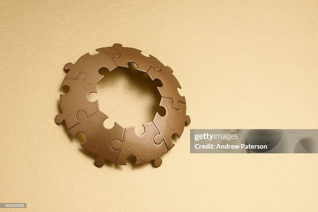 Circle of gold jigsaw pieces