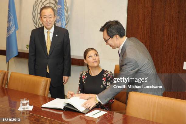 United Nations Secretary-General Ban Ki-moon looks on as Crown Princess Victoria of Sweden signs the UN guest book handed to her by UN Chief of...