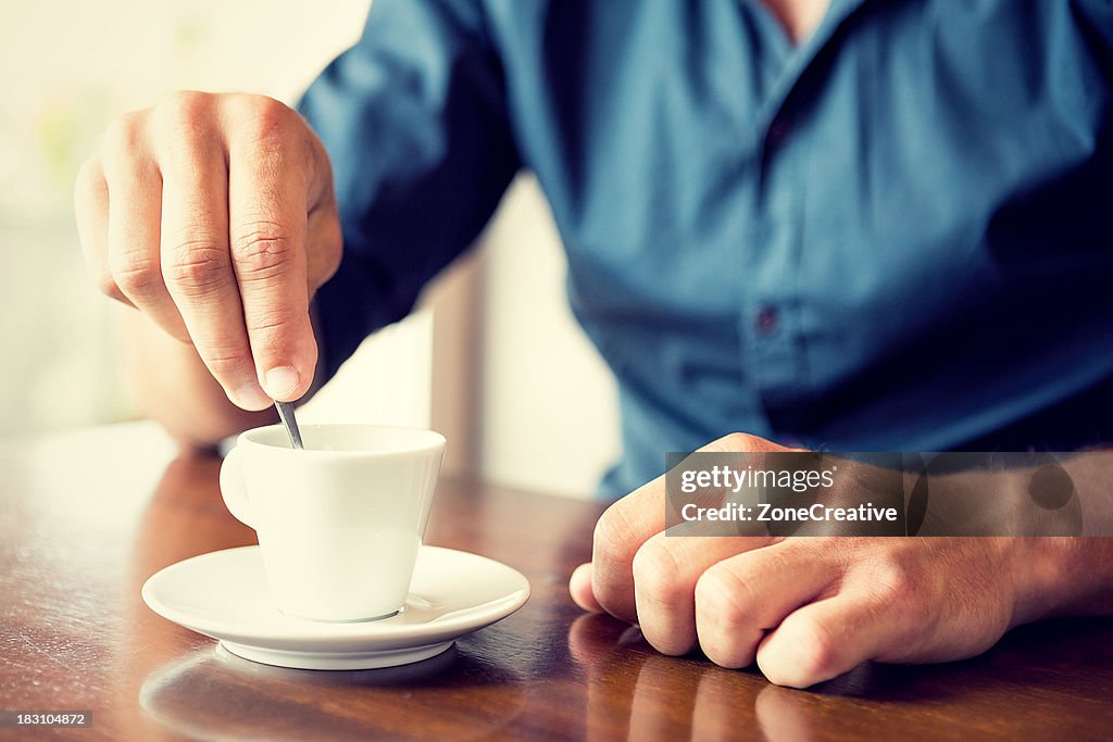 Young man blend his coffee at italian café