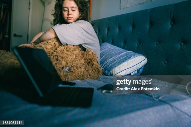 gadgets addiction of sleepy young woman in bed. laptop and smartphone are on the bed aren't best sleeping companions. - overslept stock pictures, royalty-free photos & images