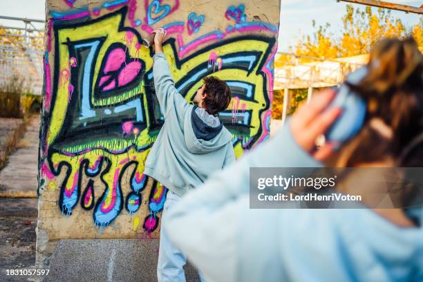 young man creating graffiti on the wall - music graffiti stock pictures, royalty-free photos & images