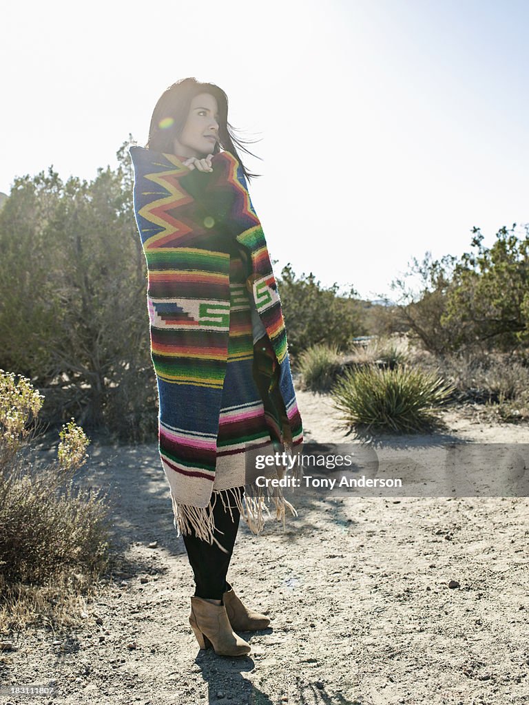 Woman in desert wrapped in colorful blanket