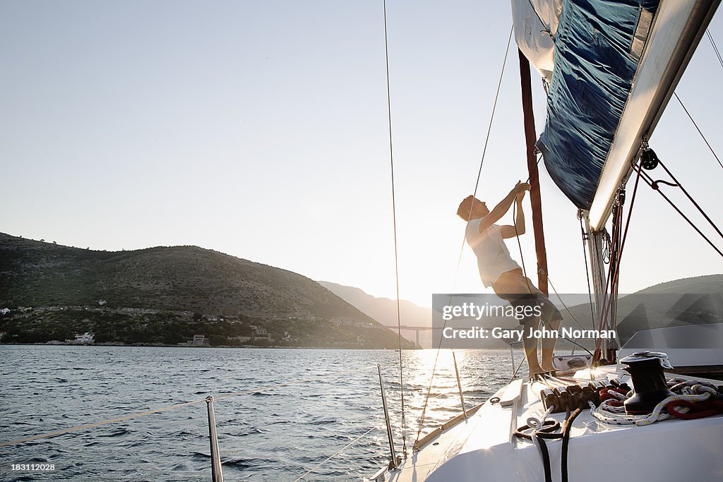 Man hoisting sail, backlit