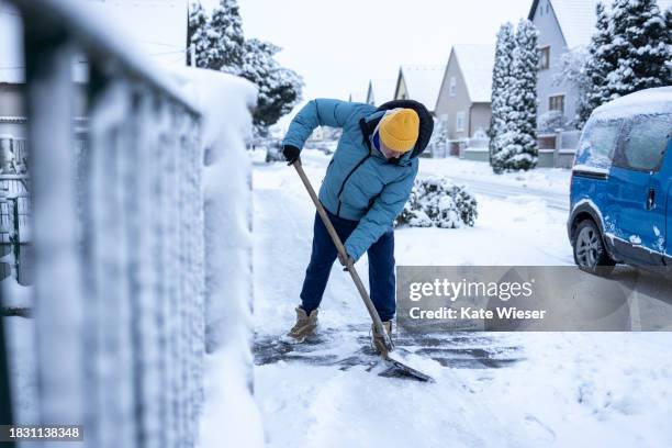 active senior man cleaning the footpath from snow with snow shovel - excavar fotografías e imágenes de stock
