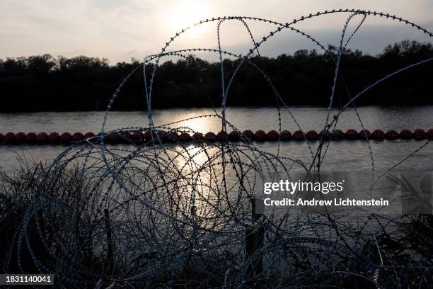 Coils of barbed wire and floating buoys surround the banks of the Rio Grande River on the Texas side of the border with Mexico, November 30 in Eagle...