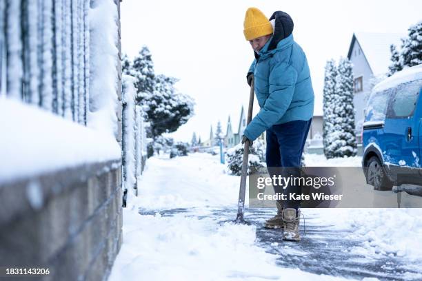 active senior man cleaning the footpath from snow with snow shovel - winter snow shovel stock pictures, royalty-free photos & images